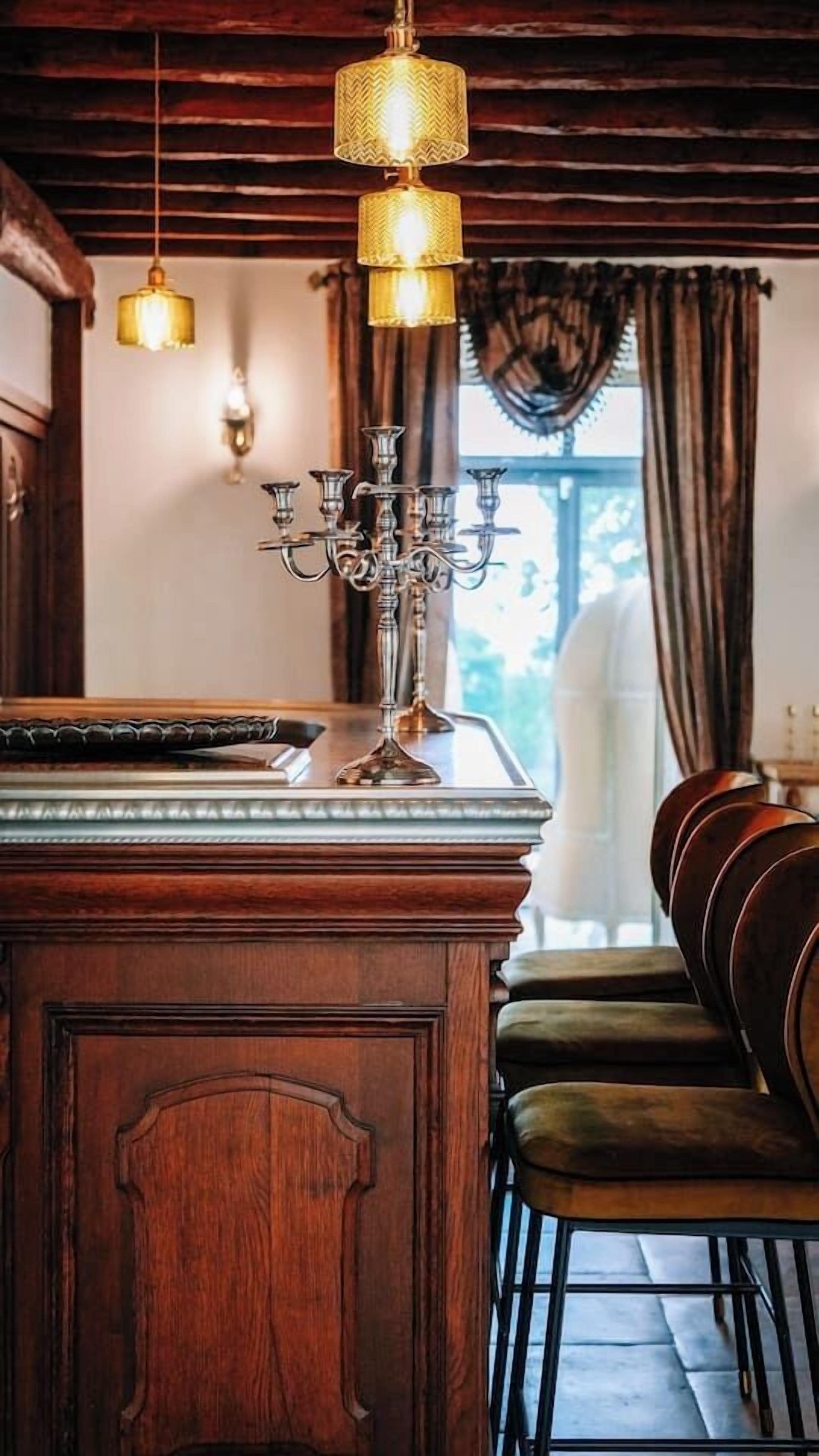 Una zona de bar con barra de madera, un candelabro, lámparas colgantes y vistas al exterior.