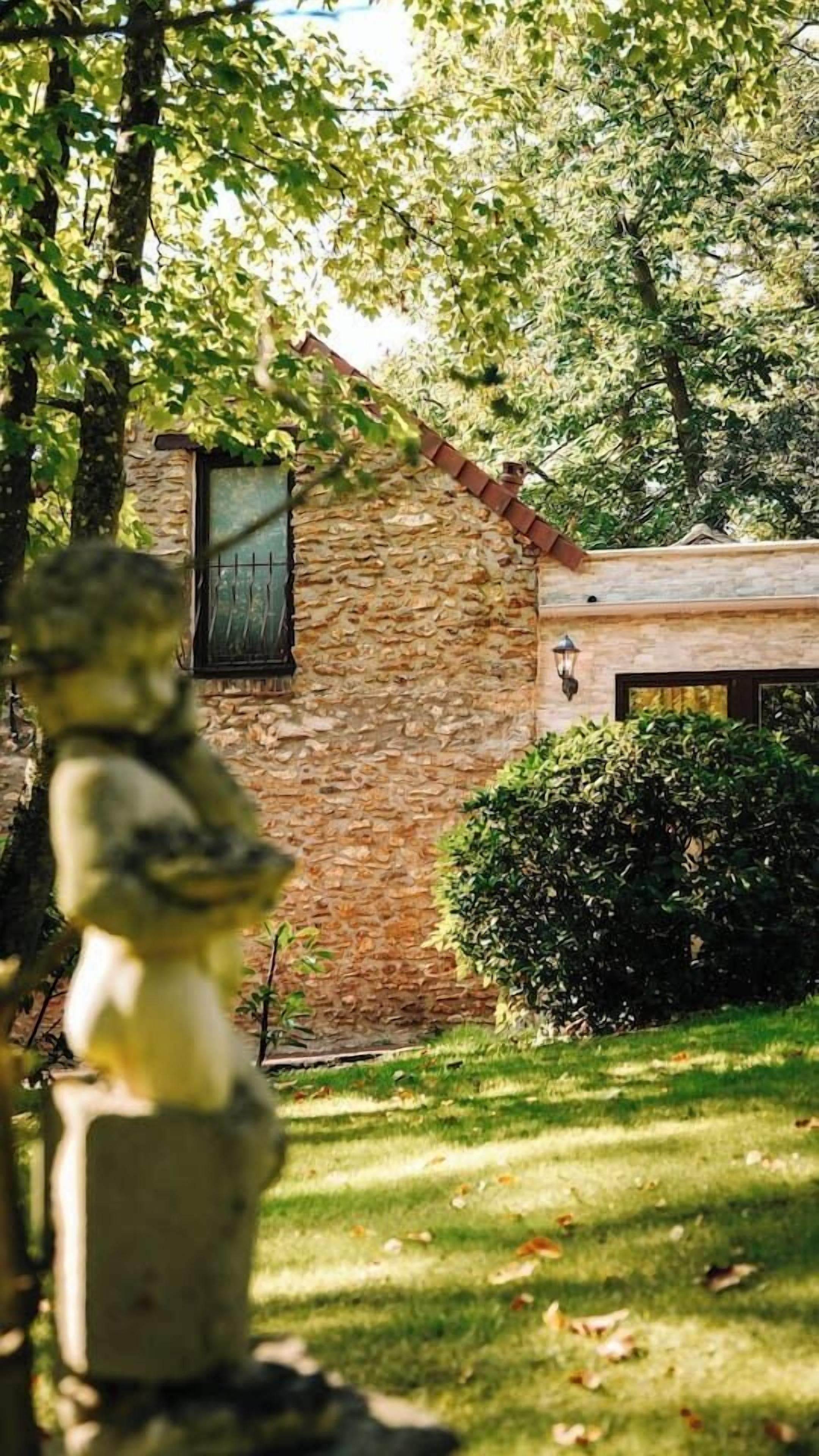Ein Steinhaus mit einem Fenster und einer Statue davor.