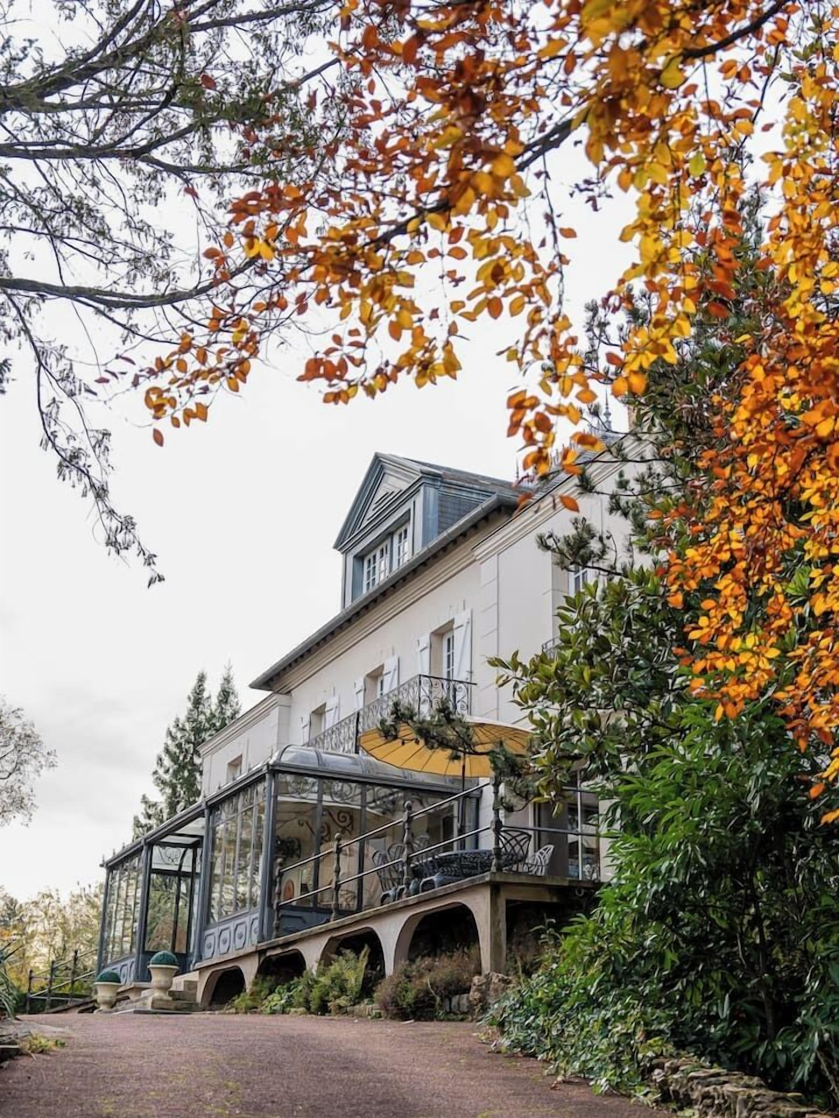 Un grande edificio bianco con una serra in vetro e un balcone.
