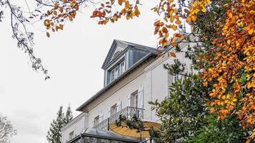 Un grande edificio bianco con una serra in vetro e un balcone.