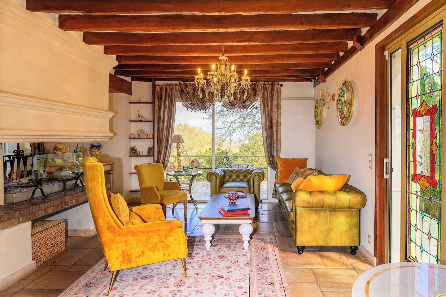 A cozy living room with a fireplace, comfortable seating, and a large window with a view.