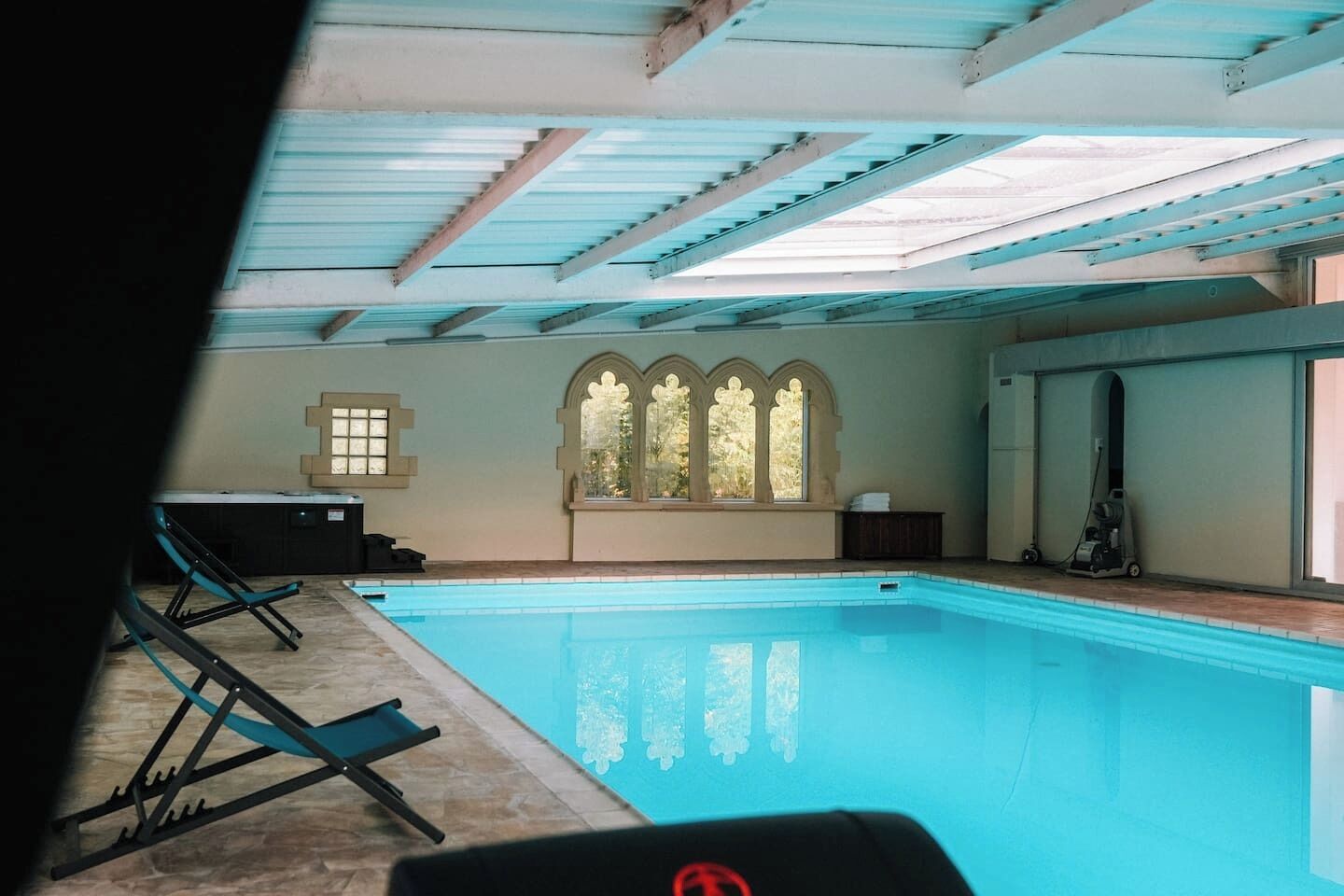 A swimming pool with a view of a building's interior, including a window with a decorative arch and a ceiling with skylights.