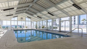 Una piscina interior con vistas despejadas al exterior, grandes ventanales y techo de azulejos.