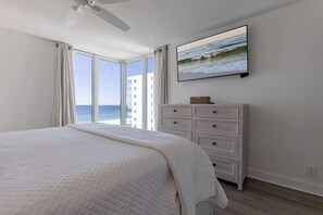 Une chambre avec un lit, une commode, une télévision et une vue sur l’océan.