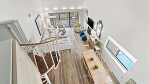 Amplia sala de estar con escalera, mesa de comedor y zona de estar con sofás y sillones.