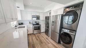 Una cocina moderna con armarios blancos, electrodomésticos de acero inoxidable y piso de madera.