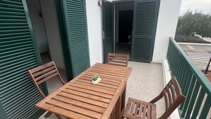A wooden table and chairs on a balcony with green shutters and a white wall. - HOUSE LA ESTRELLA PLAYA BLANCA LANZAROTE (Playa Blanca)