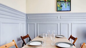 A dining table set with plates, glasses, and cutlery, surrounded by wooden chairs.