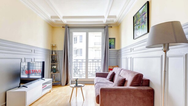 A living room with a TV, sofa, and lamp.