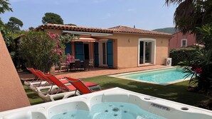 Un jardin avec une piscine, un jacuzzi et un espace salon extérieur.