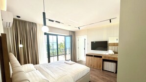 Une chambre d’hôtel moderne dotée d’un grand lit, d’un bureau, d’une télévision à écran plat et d’un balcon avec vue.