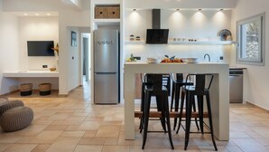 Una cucina moderna con isola centrale, sgabelli da bar, forno a incasso e televisione a schermo piatto.