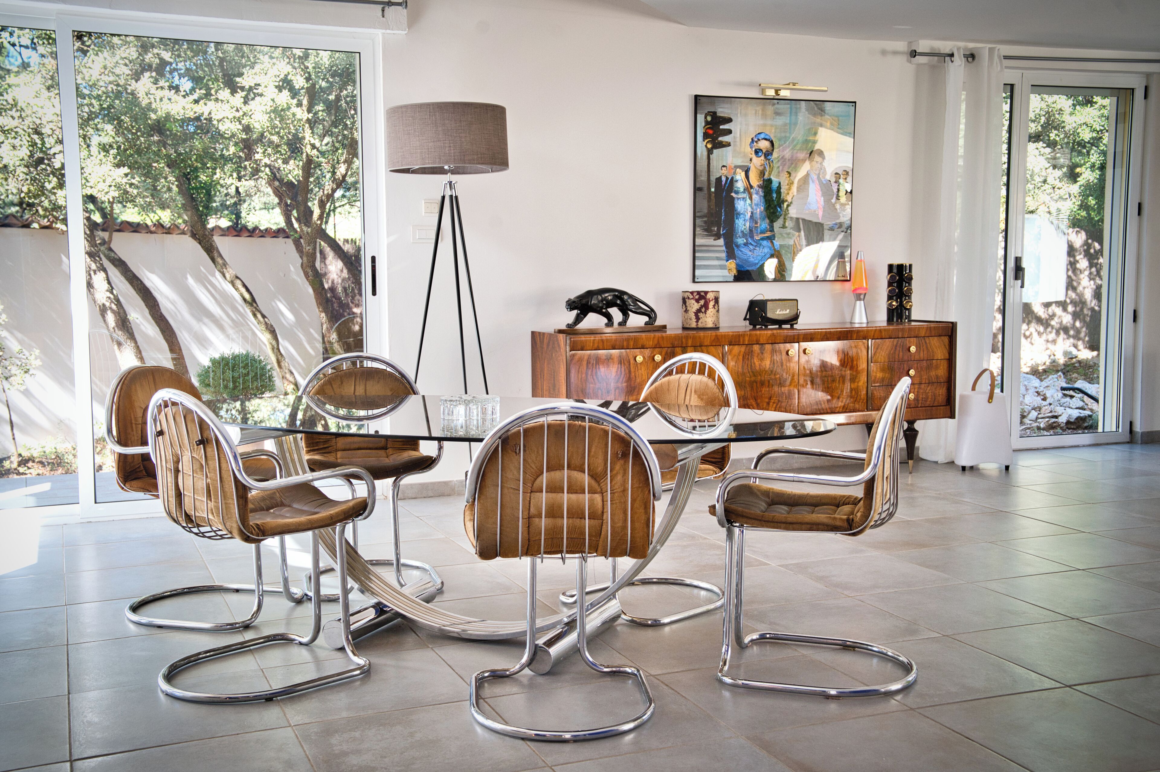 Un coin repas avec une table ronde et quatre chaises, un lampadaire, un meuble contenant des objets décoratifs et un tableau au mur.