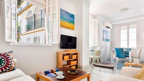 A modern living room with a wooden coffee table, a sofa, and a clear chair. There is a TV mounted on the wall and a bookshelf with wooden boxes. - Cozy Apartment in the Center. Pasaje Santa Cruz II (Seville)