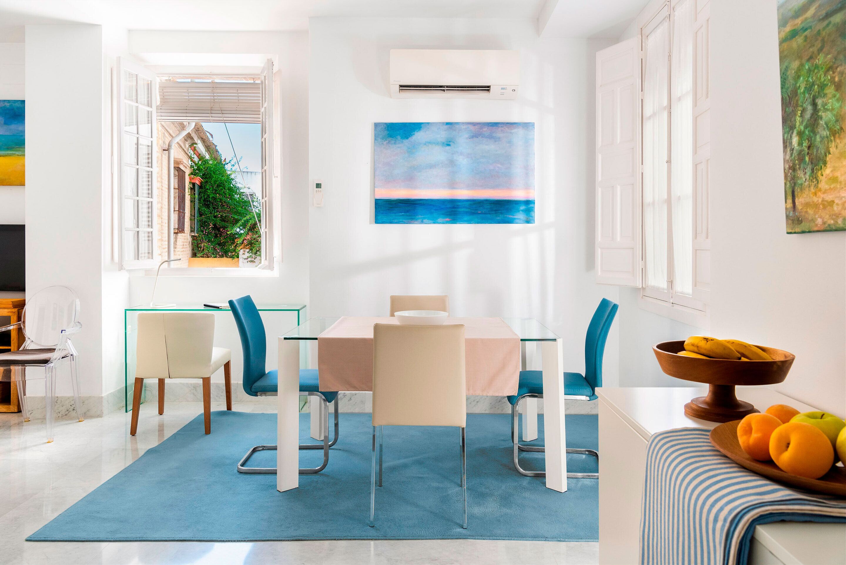 A modern dining area with a table, chairs, and a view of the outdoors.