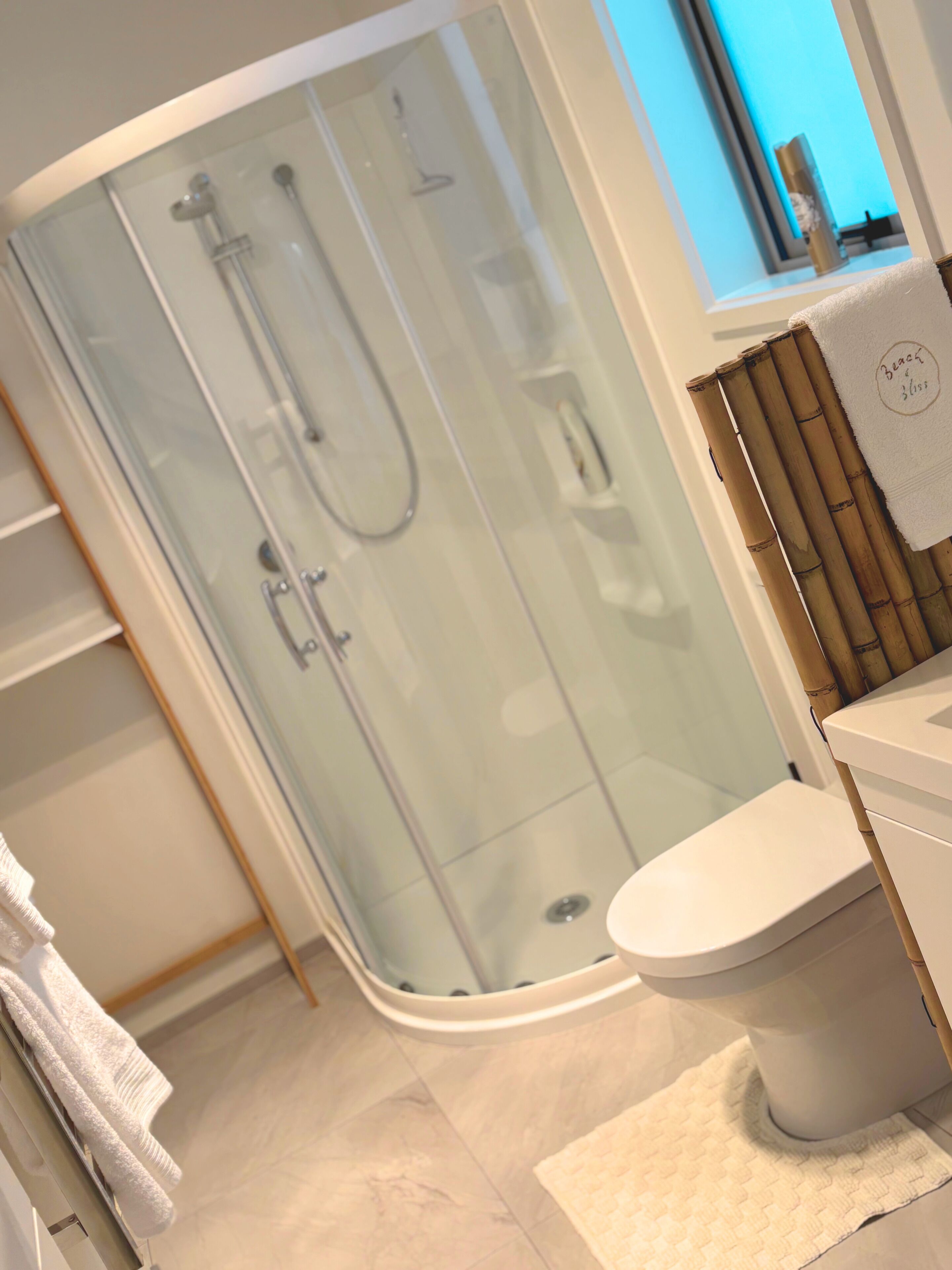 Ein modernes Badezimmer mit einer gläsernen Dusche, einer weißen Toilette und einer Bambus-Bade-Matte.