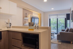 A modern kitchen with built-in appliances, a dining area with a sofa, and large windows offering a view of the outdoors. - w Bright 1BR w Balcony in Miraflores (Lima)