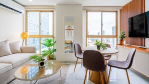 A modern living room with a sofa, dining table, chairs, a coffee table, and a TV. - w Amazing 1BR in Obarrio (Panama City)