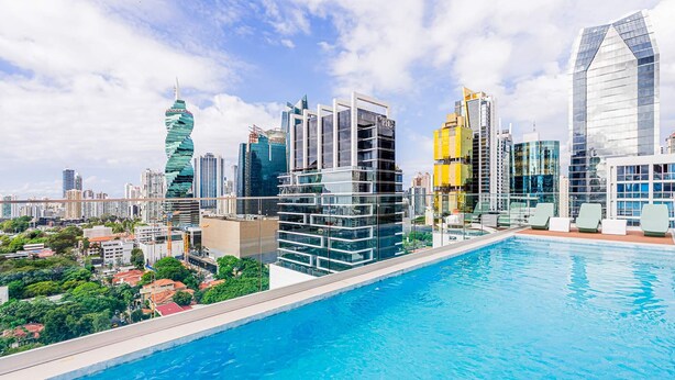 A modern cityscape with a prominent twisting skyscraper, a high-rise building with a glass facade, and a swimming pool area. - w Amazing 1BR in Obarrio (Panama City)