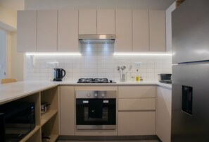 A modern kitchen with a built-in oven, a stainless steel refrigerator, and a gas stove. - w Charming 2BR w Balcony in Miraflores (Lima)