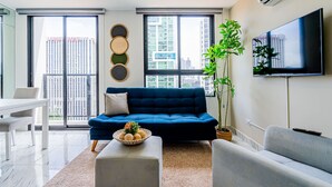 Una sala de estar moderna con un sofá azul, una mesa blanca y un ventanal con vistas a la ciudad.