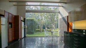 A modern kitchen with a large window, a dining area with chairs, and a kitchen island. - w Elegant 5BR Home w Pool in Cieneguilla (Pachacámac)