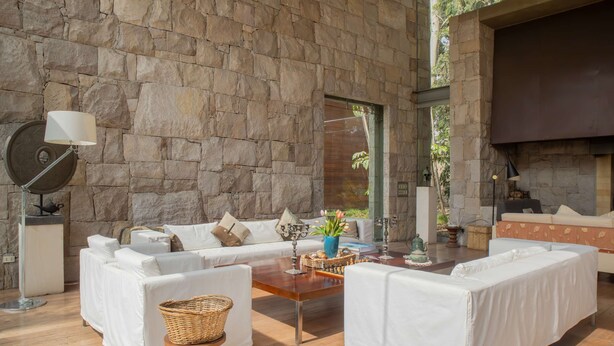 A modern interior with stone walls, a sofa set, a wooden coffee table, and a lamp. - w Elegant 5BR Home w Pool in Cieneguilla (Pachacámac)