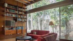 A modern living room with a red sofa, a coffee table, and a bookshelf. - w Elegant 5BR Home w Pool in Cieneguilla (Pachacámac)