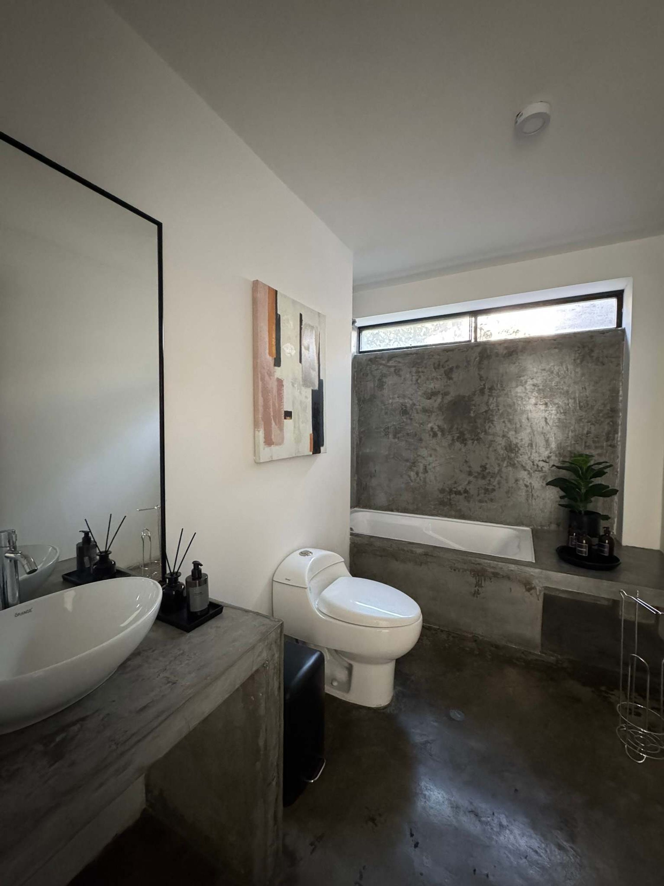 Un baño moderno con un espejo grande, un lavabo blanco, un inodoro y una bañera.