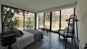 Un dormitorio con una cama grande, una silla, un banco y un perchero.