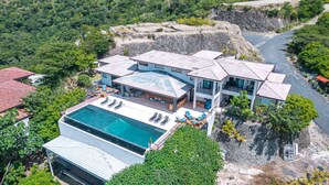 A modern multi-story house with a large swimming pool, multiple balconies, and lush surrounding vegetation. - w Breathtaking 9BR Villa in Costa Rica (Cabo Velas)