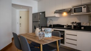 A modern kitchen with white cabinets, a stainless steel refrigerator, a microwave, and a dining table with chairs. - Stunning 1BR With Great Deco in Miraflores (Lima)