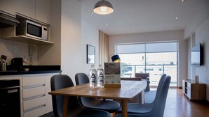 A modern kitchen with a microwave, a dining table with chairs, and a large window offering a view of the city. - Stunning 1BR With Great Deco in Miraflores (Lima)