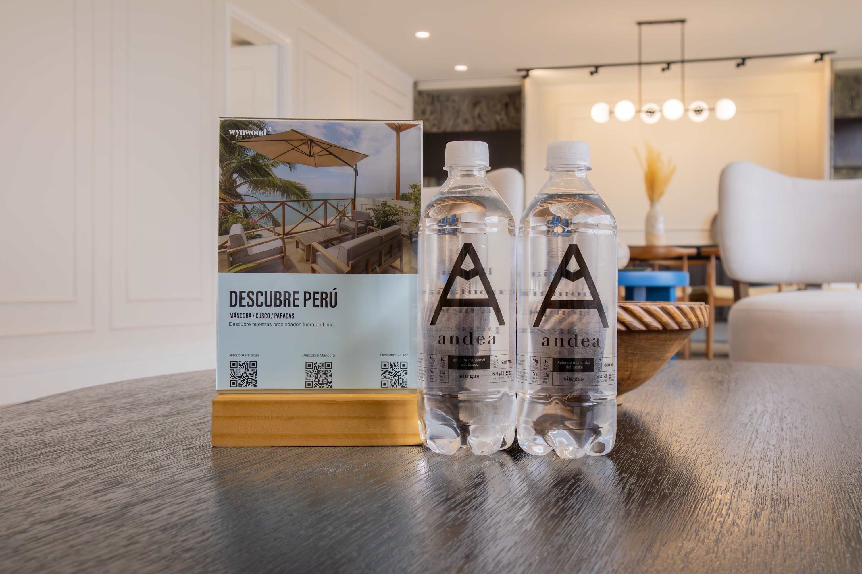 A table with two bottles of water and a brochure on a wooden stand.