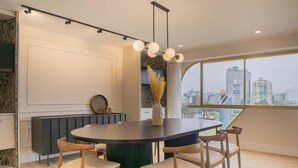 Un comedor moderno con una mesa redonda, sillas de madera y vistas a la ciudad a través de amplias ventanas.