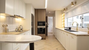 Una cocina moderna con armarios blancos, encimera de mármol y electrodomésticos integrados.