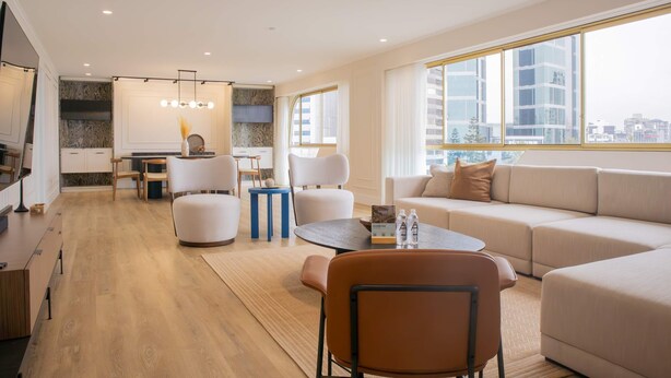Una sala moderna con un sofá, sillas, una mesa baja y una zona de comedor con una mesa y sillas.