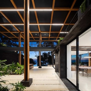 A modern outdoor patio area with a wooden ceiling structure, a seating area with tables and chairs, and a view of the surrounding landscape. - w Spectacular 4BR Villa in Costa Rica (Jacó)
