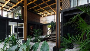A modern interior with a wooden ceiling structure, a staircase, and lush indoor plants. - w Spectacular 4BR Villa in Costa Rica (Jacó)