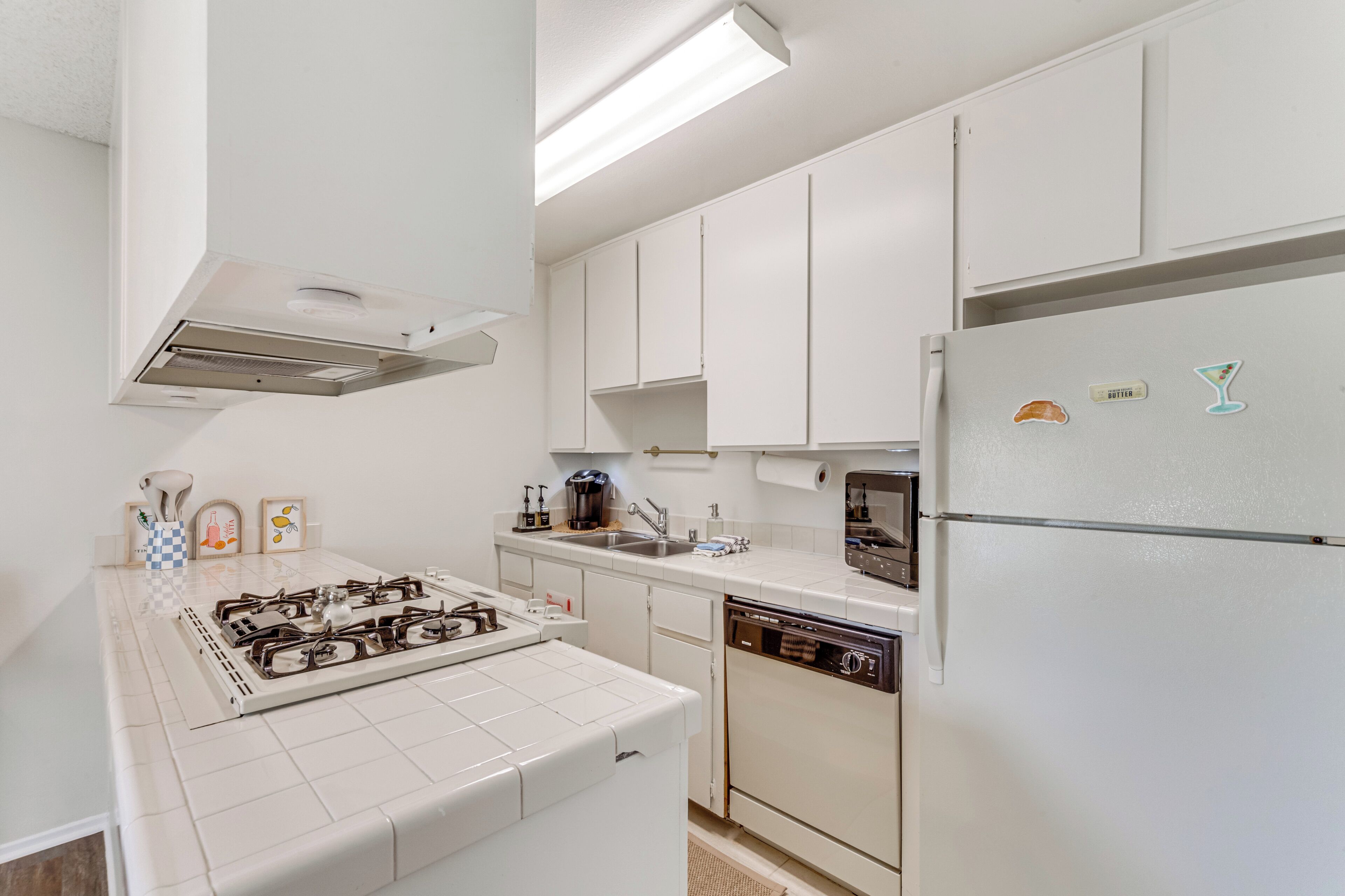 Una cocina moderna con armarios blancos, una estufa a gas, un lavavajillas y un refrigerador.