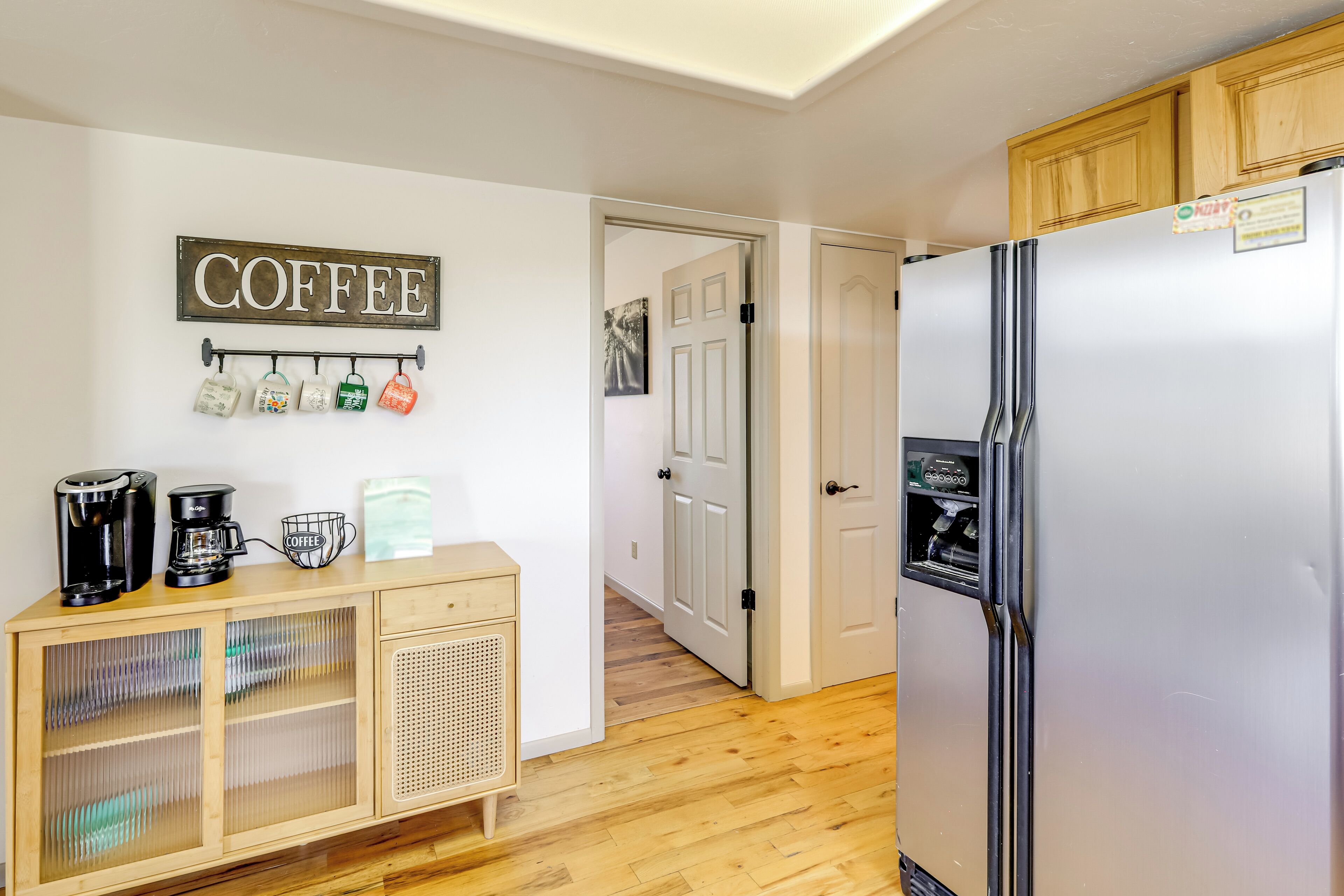 Une cuisine équipée d’un coin café, d’un réfrigérateur et de meubles de rangement en bois.