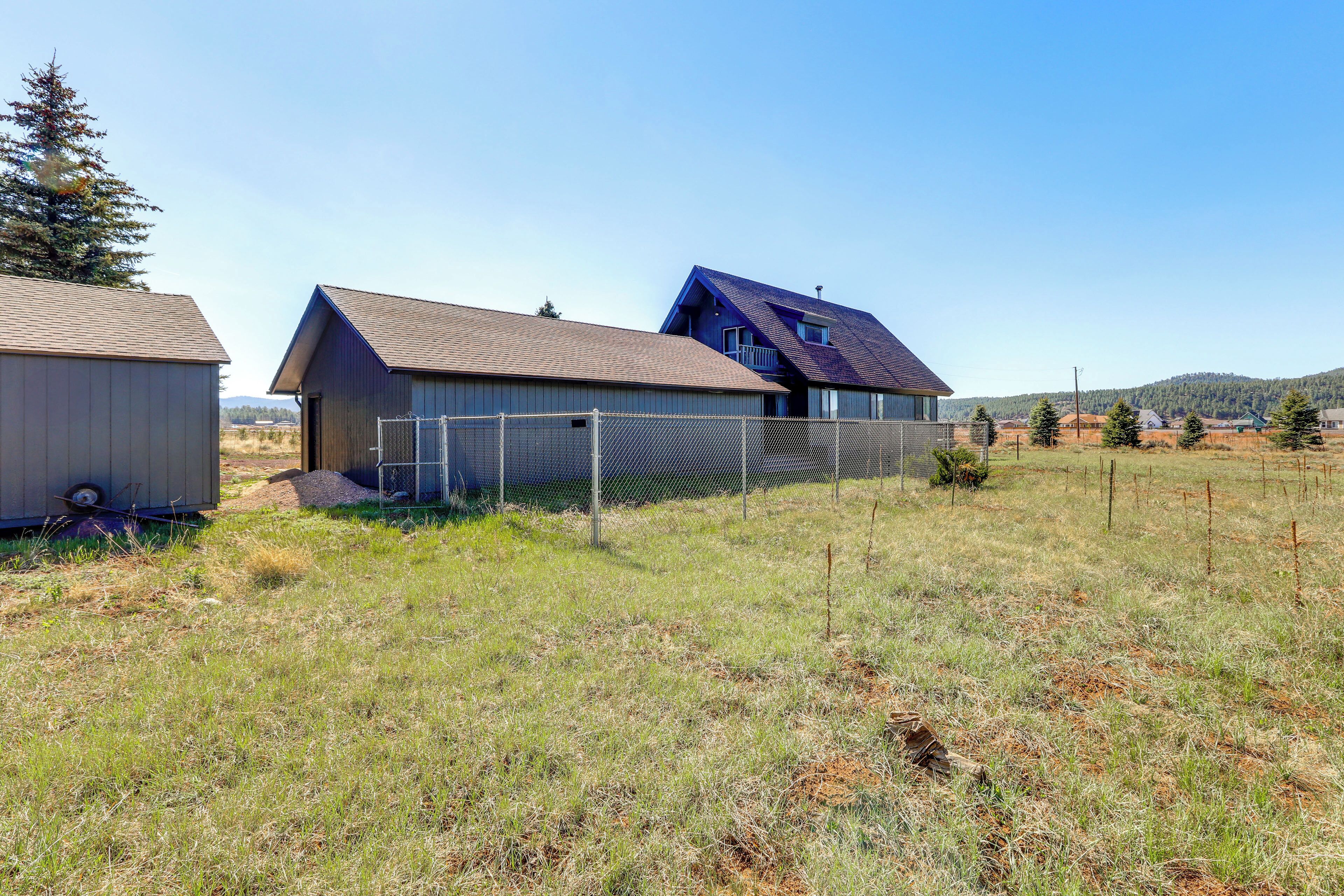 A modern house with a sloped roof, a fenced yard, and a clear sky.