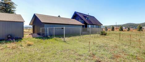 A modern house with a sloped roof, a fenced yard, and a clear sky.