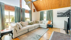 Una sala moderna con un amplio sofá modular, un televisor de pantalla plana y un techo de madera.