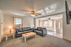 A living room with a sectional sofa, a coffee table, a lamp, and a ceiling fan.