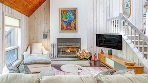 Una sala de estar acogedora con chimenea, televisión y una escalera.
