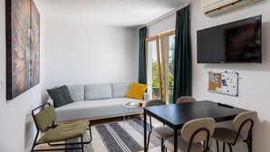 A modern living room with a grey sofa, a small table, and a TV mounted on the wall. - Holiday Home Olive&sun (Zupa dubrovacka)