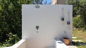 A white outdoor structure with a water spout, a metal door, and a potted plant. - Holiday Home Olive&sun (Zupa dubrovacka)
