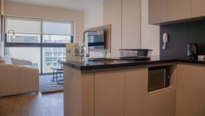 Een moderne keuken met een ingebouwde magnetron, een koffiezetapparaat en een spoelbak.