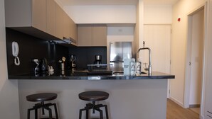 Een moderne keuken met een zwart aanrecht, roestvrijstalen apparatuur en twee krukken.